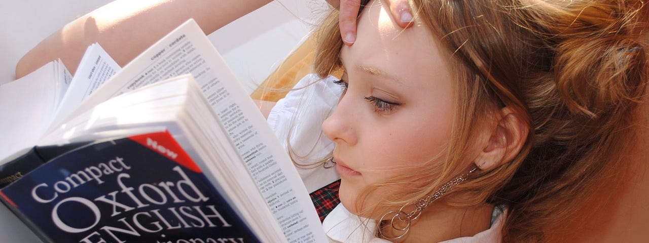 A yiung school girl reading the Oxford Dictionary.