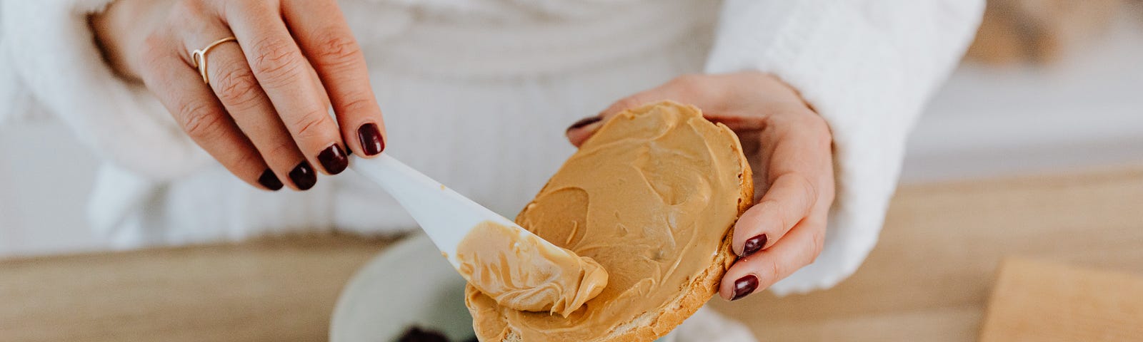 Close up of a person spreading peanut butter on toast.