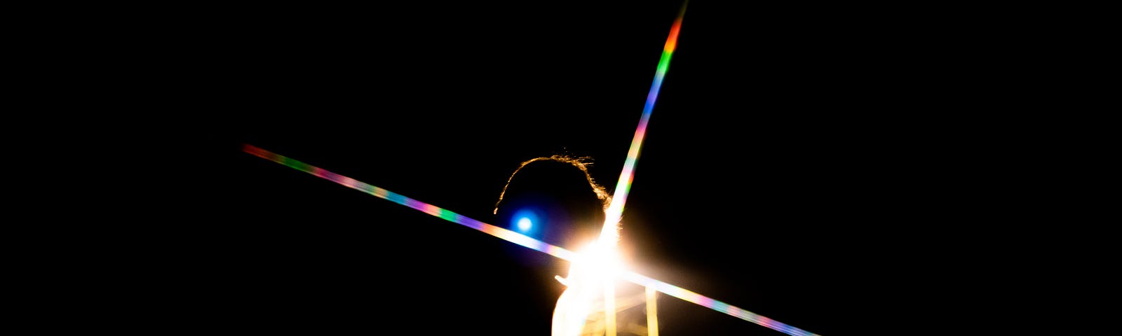 Rainbow lights from a prism on a candle in the dark.