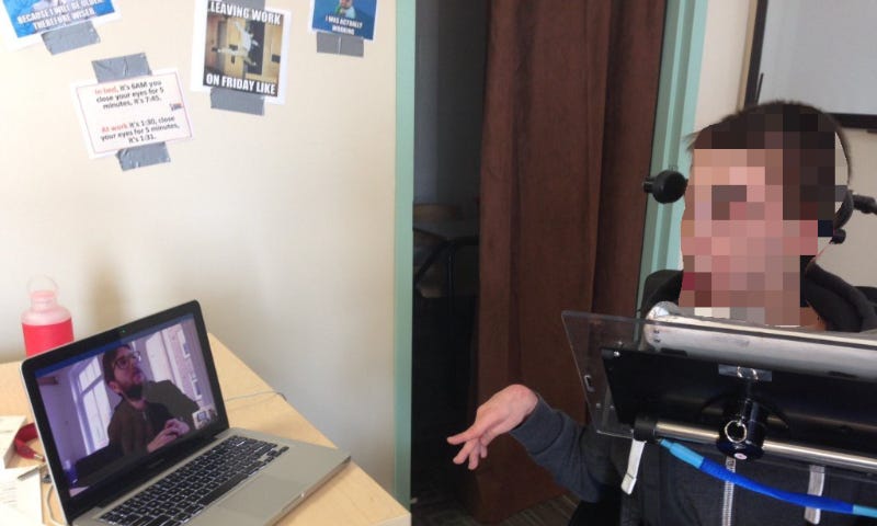 Remote usability testing, person in a wheelchair is looking at a screen with Dean looking back.