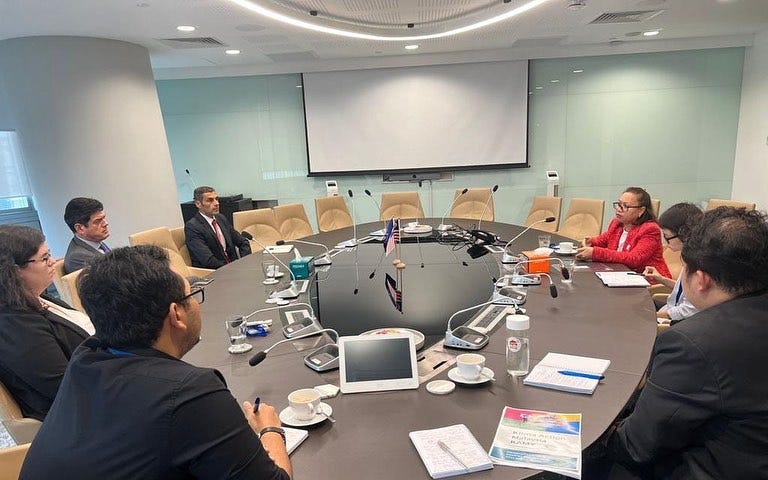 Image of 7 people sitting around a table, in a meeting.