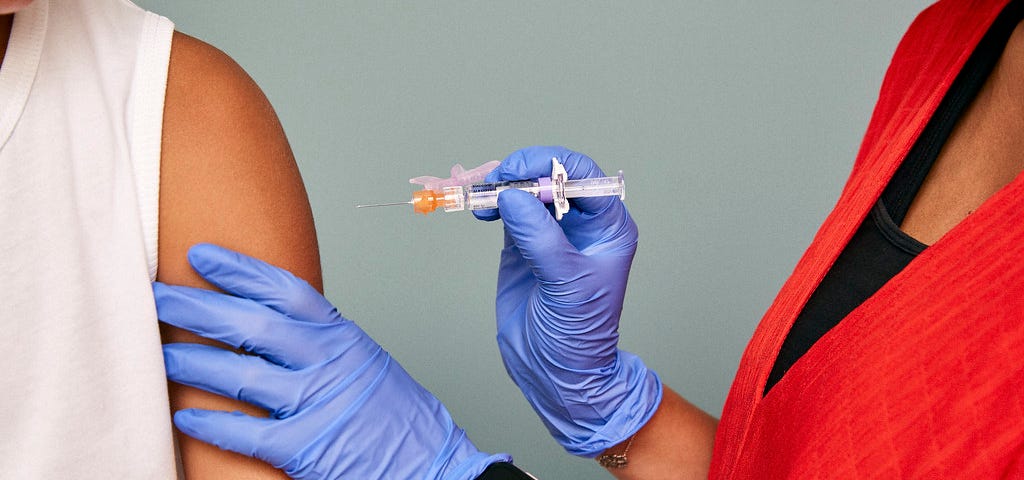 “Closeup of doctor’s hands, vaccine, and arm” by SELF Magazine is licensed with CC BY 2.0.