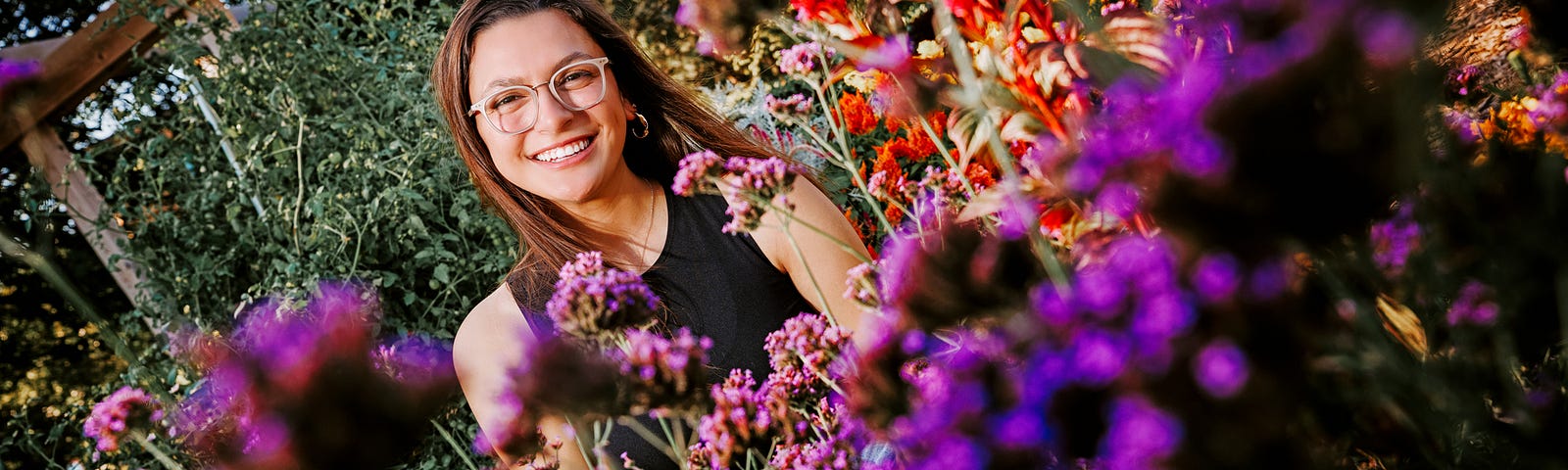 Isabella smiles for a photo surrounded by flowers on East Campus
