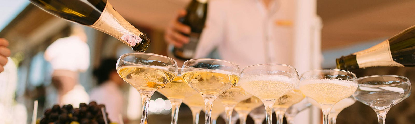 Person pouring champagne in cocktail glasses