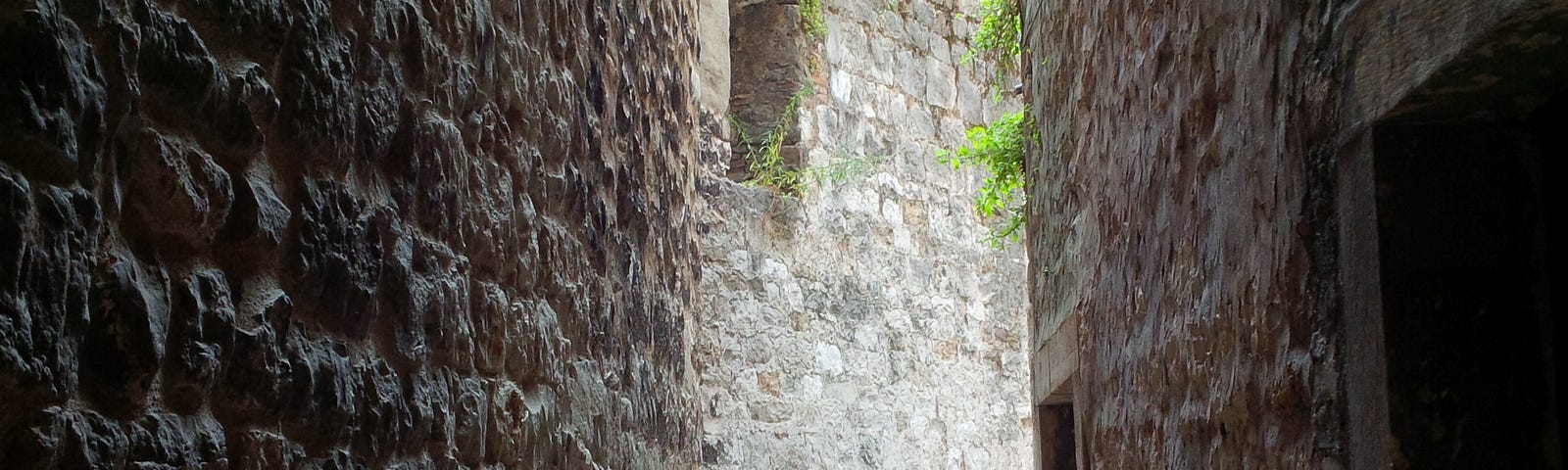 Photo by the Author - P.Tomasson May 2017 shows a narrow alley between houses in Split in Croatia, walls made of stones