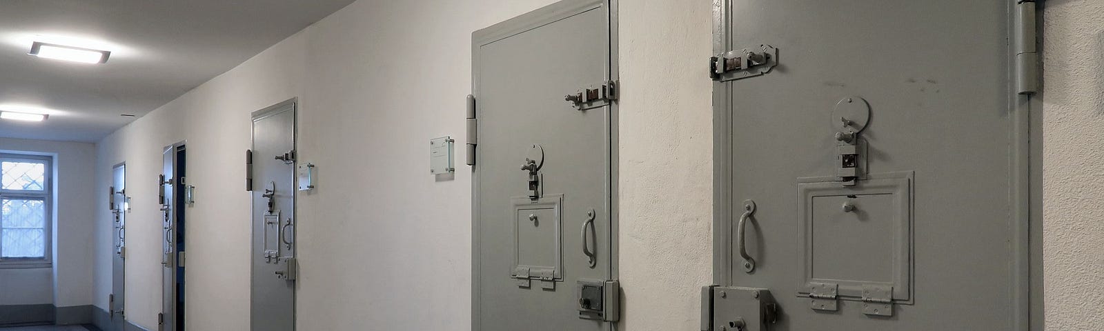 A row of jail cells on a hallway.