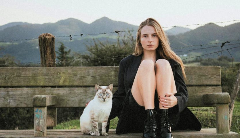 A woman and a cat sitting on a bench.