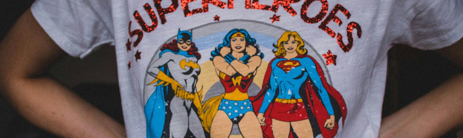 A person wearing a white t-shirt with (female) superheroes prints