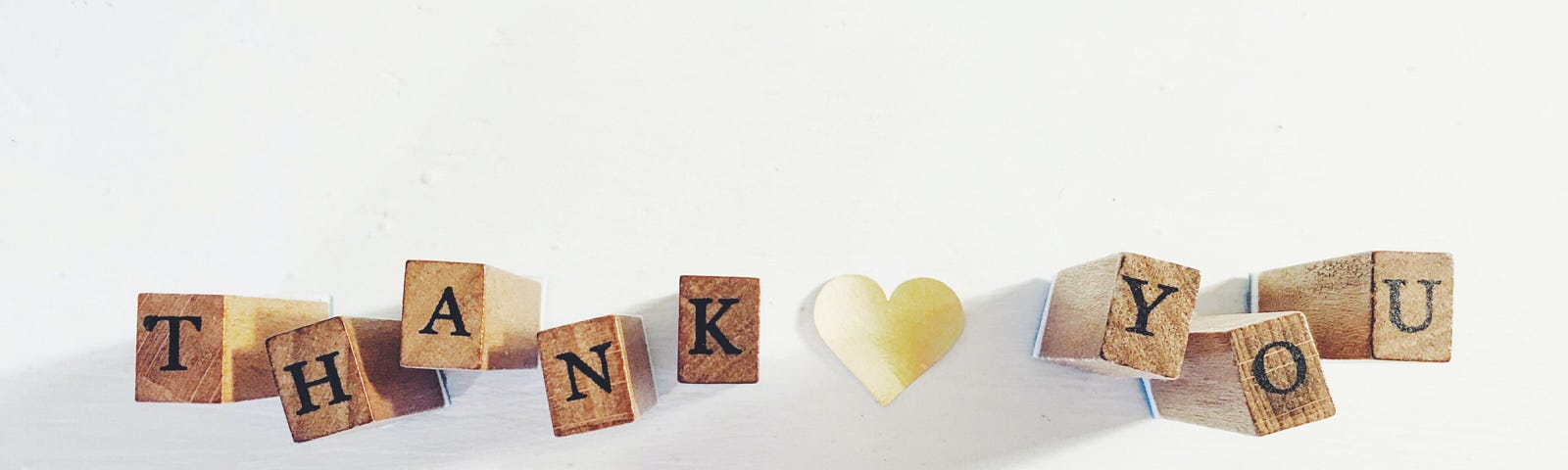 Wooden cubes with letters reading Thank you and a white heart in the middle