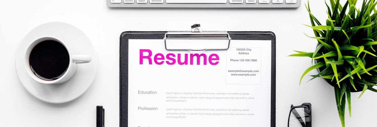 A paper copy of a resume on a clipboard near a keyboard and cup of coffee