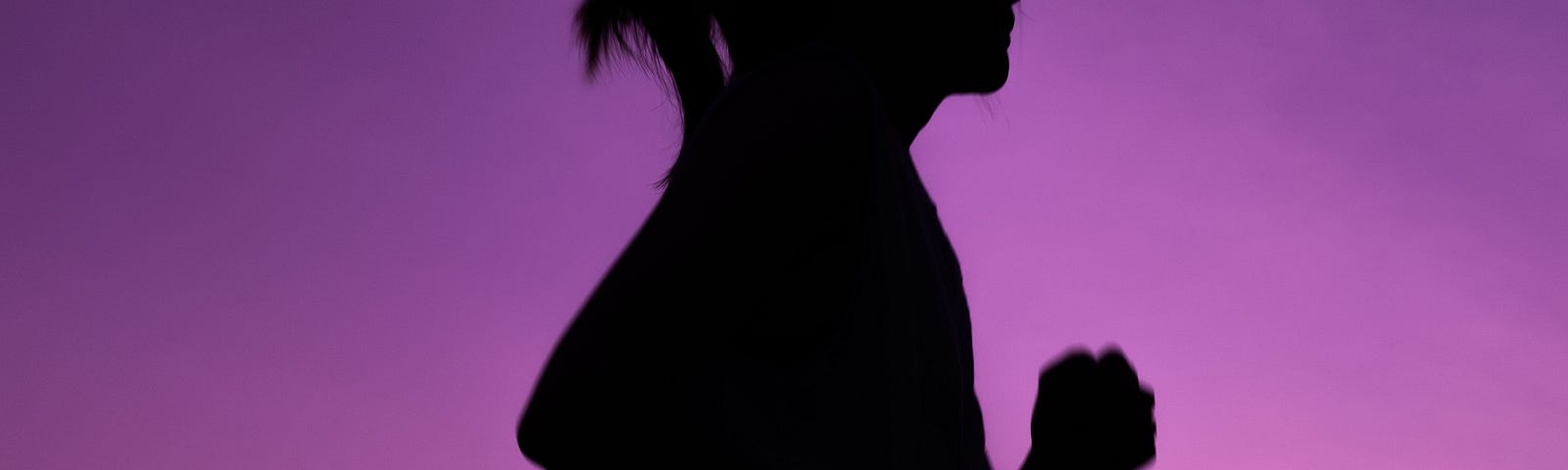 Silhouette of girl running at night, against a purple sky