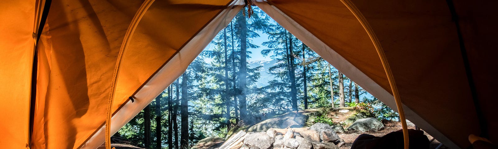 View of forest from inside tent, the tent’s opening has triangular and circular layers which resemble the GraphQL logo