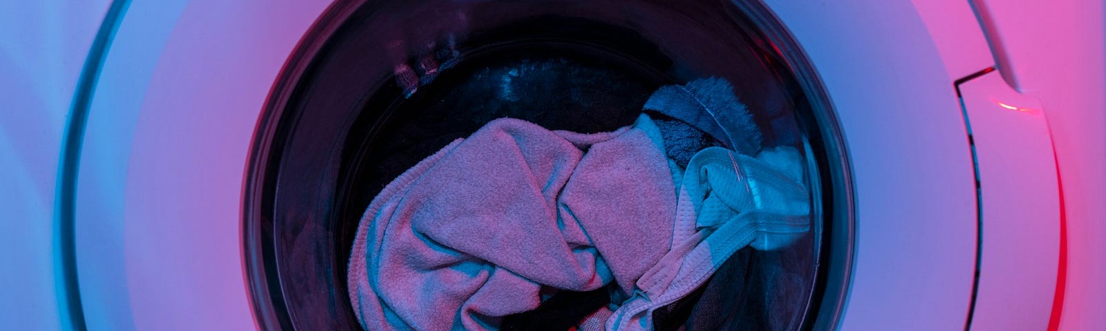 a pink lit washing machine full of clothes