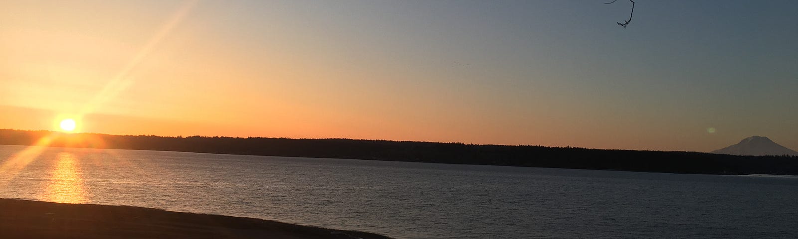 A picture of the sunrise over Puget Sound with Mount Rainier in the distance.