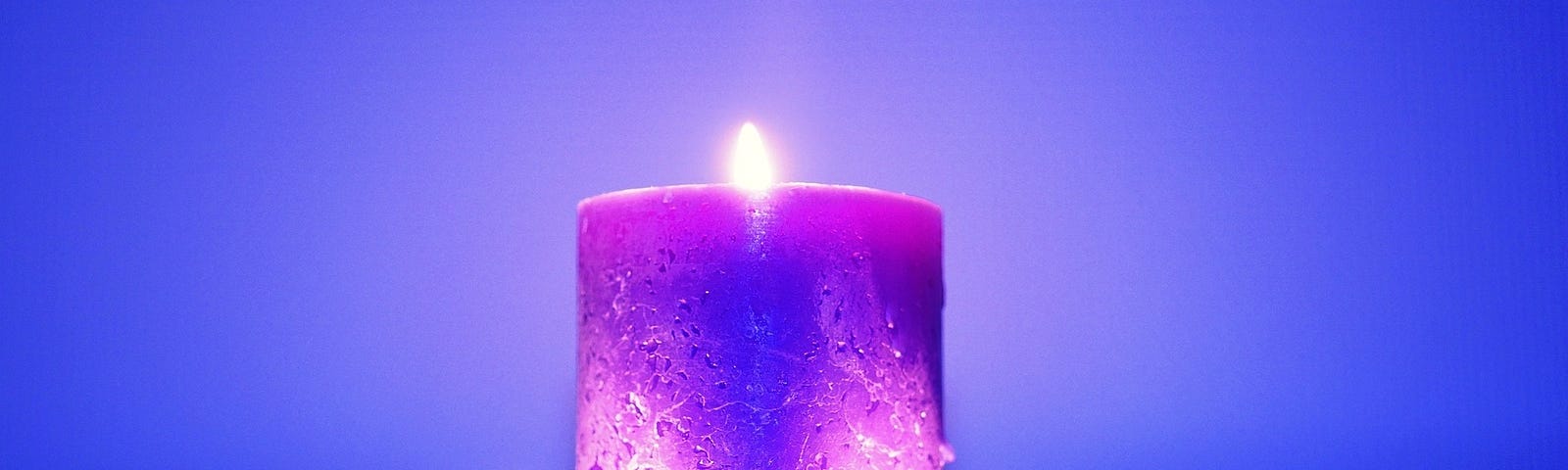 A trio of candles, two small blue ones with a larger purple one resting on top