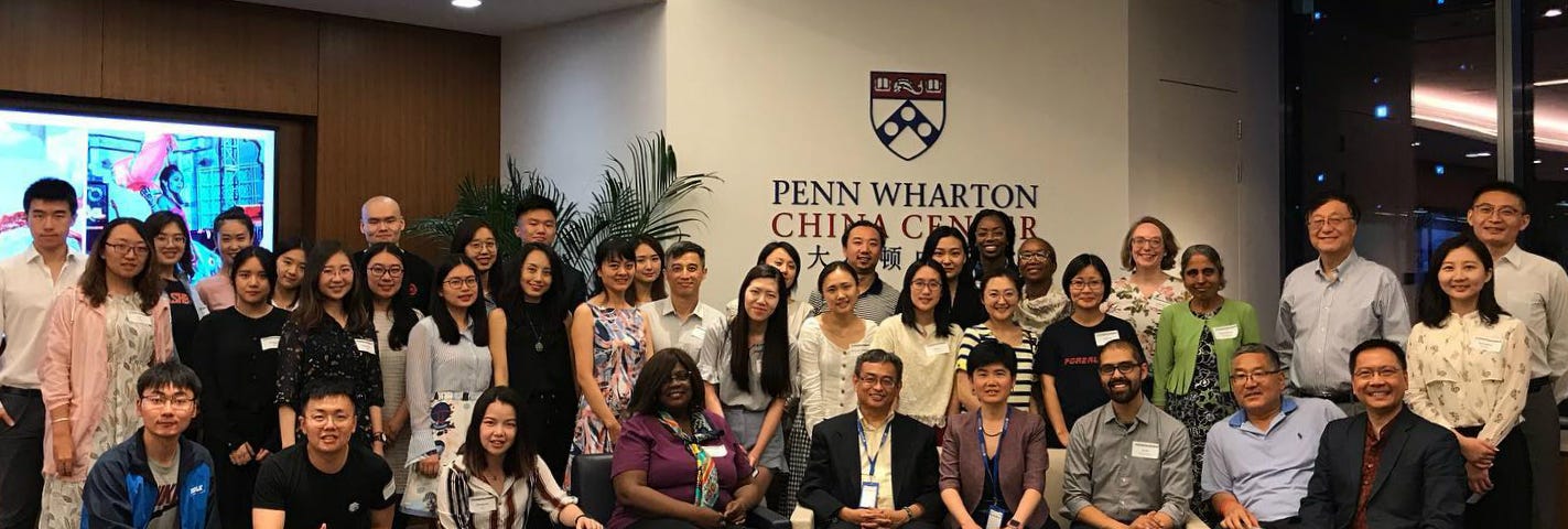 A large crowd of Forerunner 2019 participants pose in from of the Penn Wharton China Center sign.