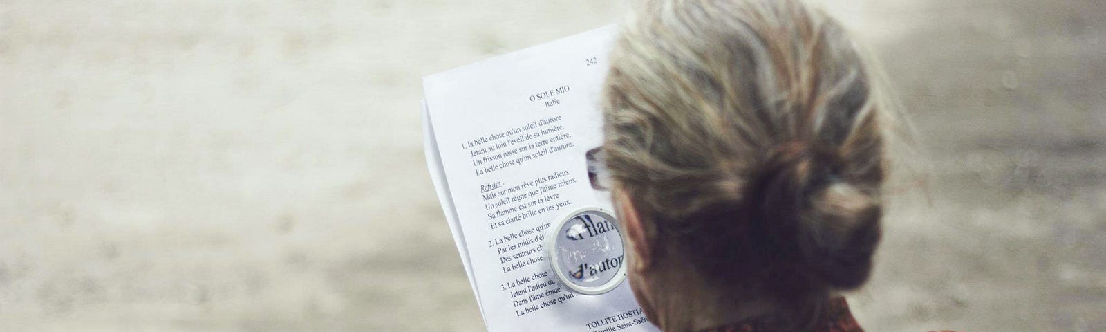 Woman reading a paper using a magnifying glass