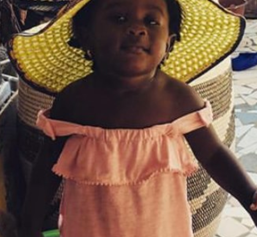 A young girl in a market stares upward into the camera.