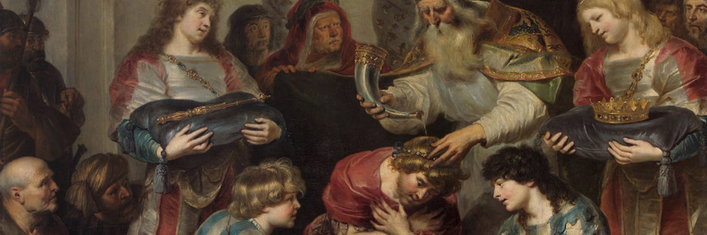 A young Solomon is wearing a red tunic and kneeling with his arms crossed and head bent over a large gold dish held by two young men in matching blue and white striped robes. More people surround him. A priest with a long white beard and mitre is pouring oil from a horn over Solomon’s head to anoint him king.
