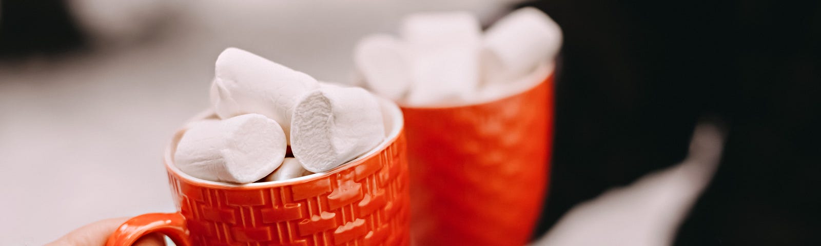 Two red mugs filled with marshmallows.