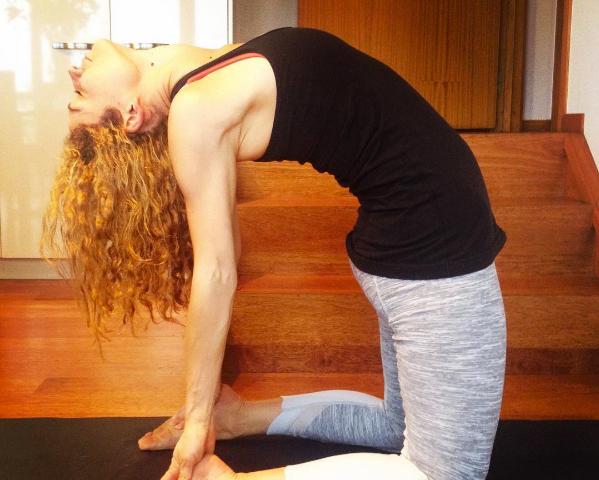 A woman stands on her shin with her hands on her heels in a classic yoga pose named Ustrasana