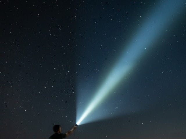 A man with a flashlight looking at the stars