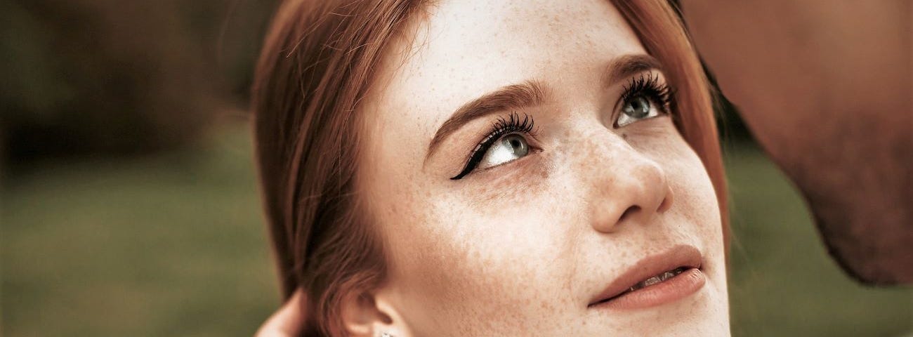 A beautiful ginger haired young woman about to be kissed.