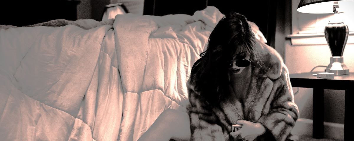 A woman playing cards with a glass of wine in her bedroom