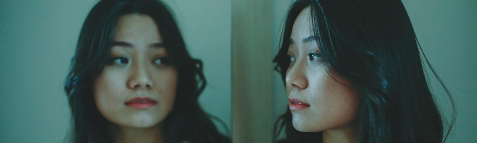 A woman studies herself in the reflection of a mirror