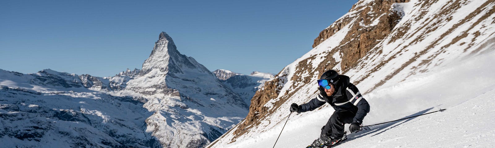 Luca Cheula skiing down a slope in Zermatt, Matterhorn in the backround.