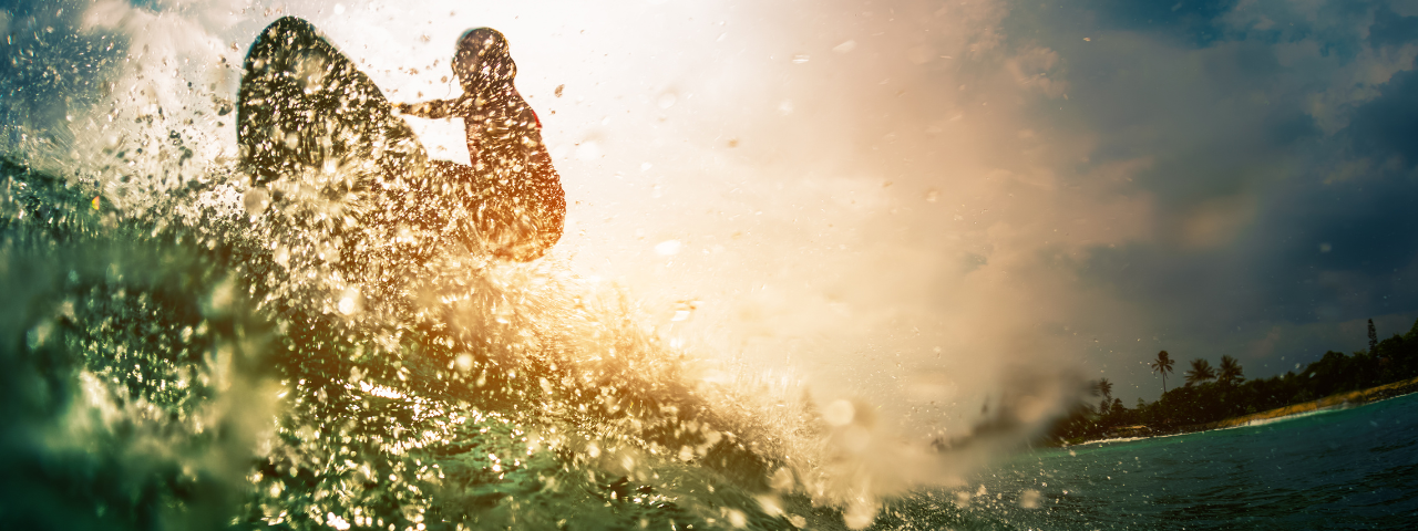 woman on a surfboard riding a wave in the fading sunlight, water spraying up