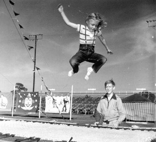 Black and white photo of little girl jumping on trampoline