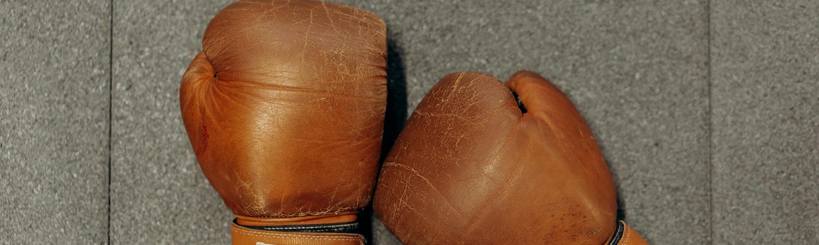 Pair of brown leather boxing gloves on gray background.