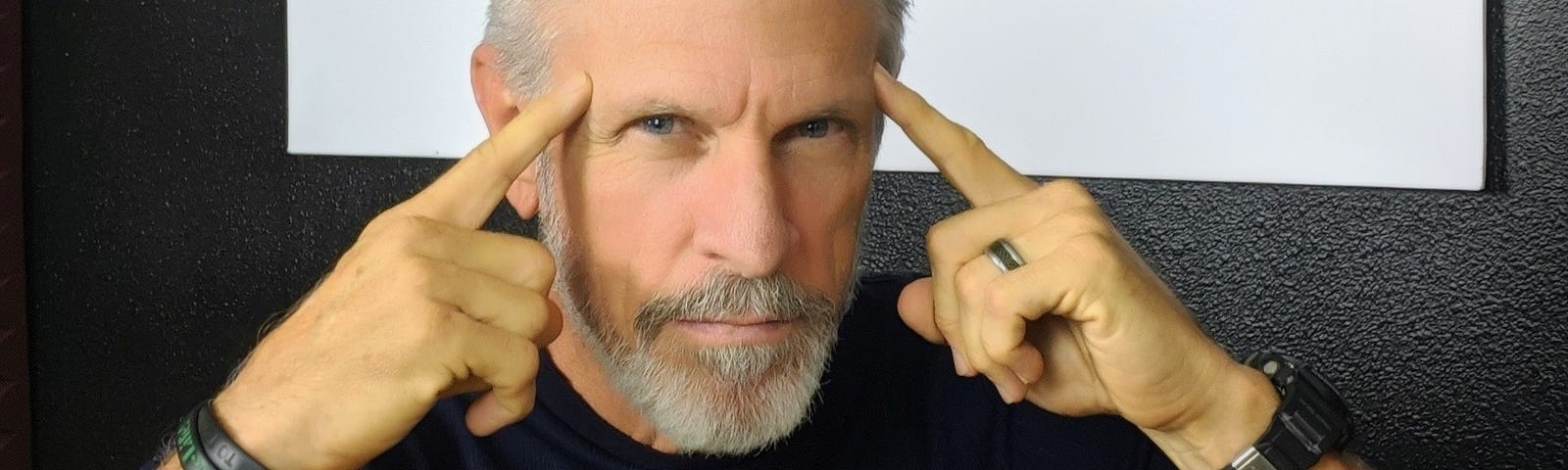 Picture of the author pointing with both index fingers at each of his temples.