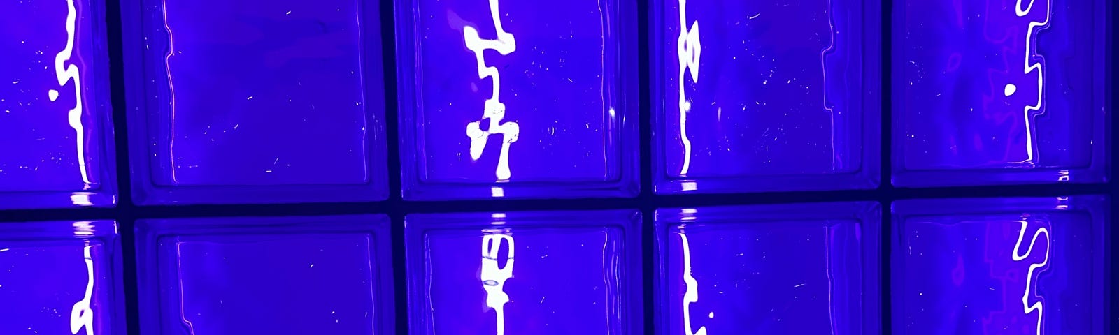 A picture of rows of bright blue glass bricks with what looks like light squiggles behind them. The abstract image is meant to evoke the transmission of thought through writing.