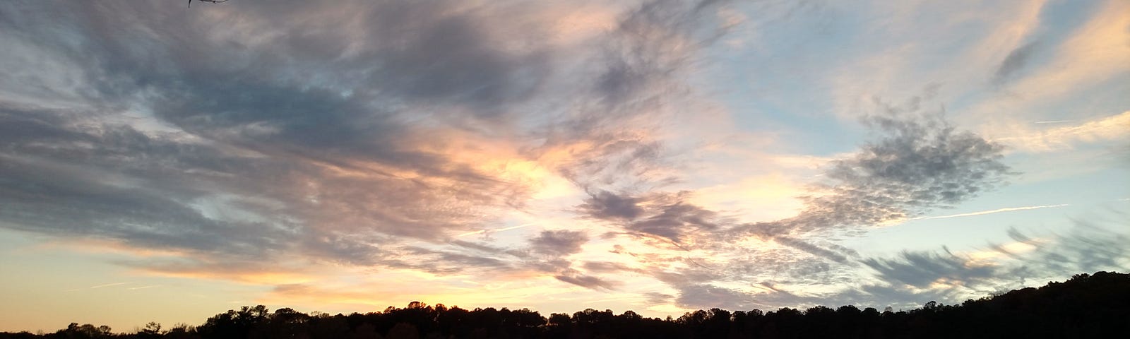 photo of sunset going down through clouds also reflected in water.