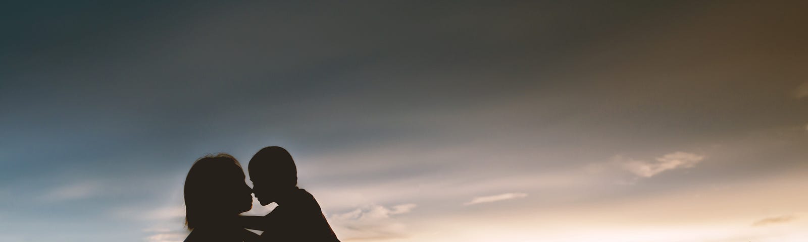 A mother and her young son embrace as the sun sets.