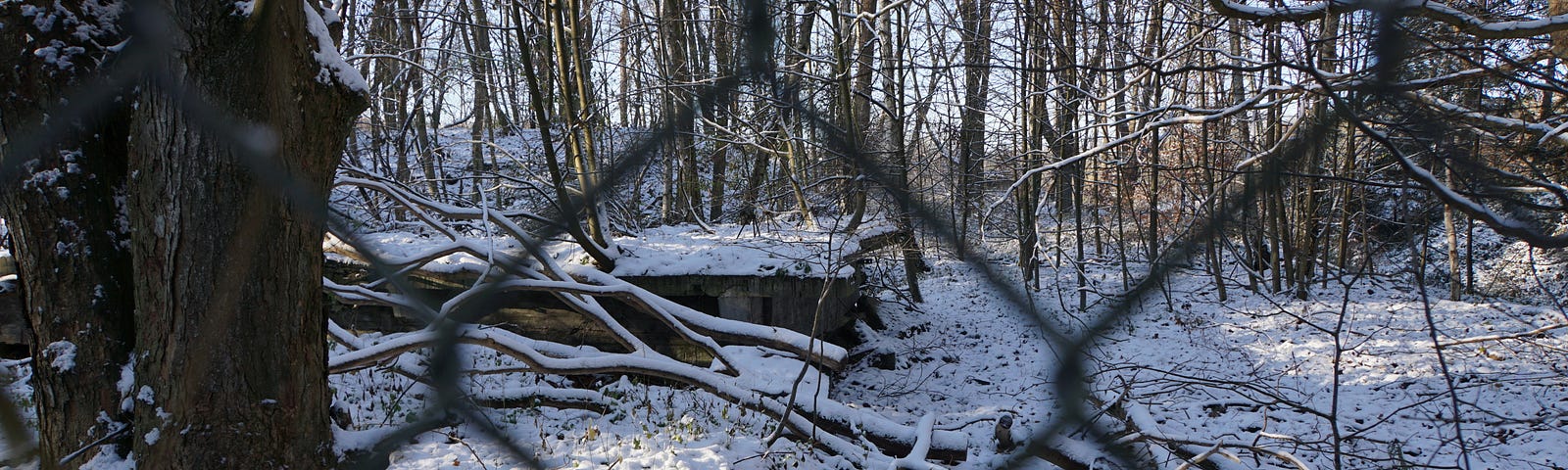 A concrete bunker with a dusting of snow behind a chainlink fence