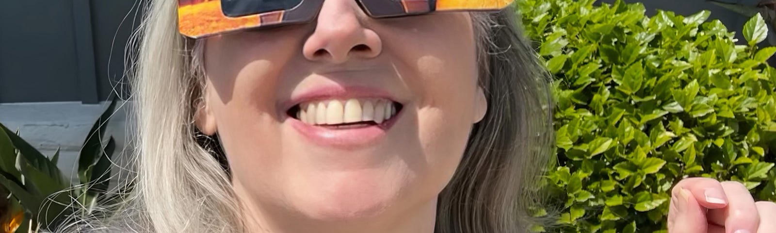 The author wearing solar eclipse glasses and looking upward smiling.