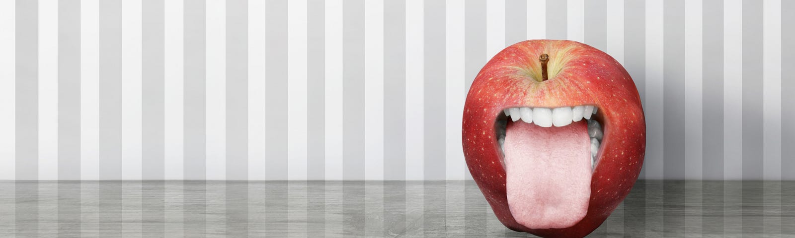 apple with a mouth with striped grey background and solid grey floor to represent the power of pictures to lure people into an article