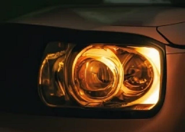 A close-up of a car headlight in the dark.