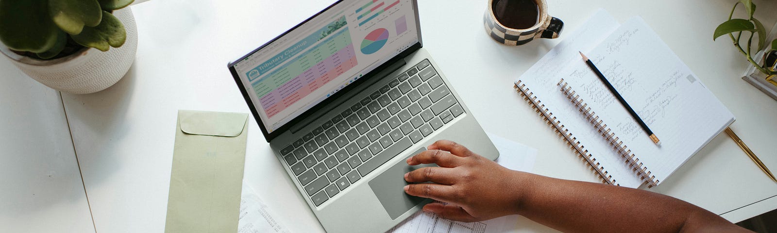 A woman types on her laptop while using a calculator