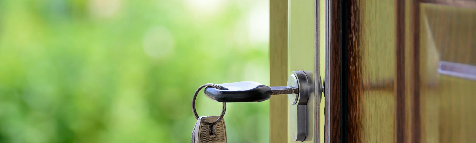 Brown wooden door standing open with silver key in lock.