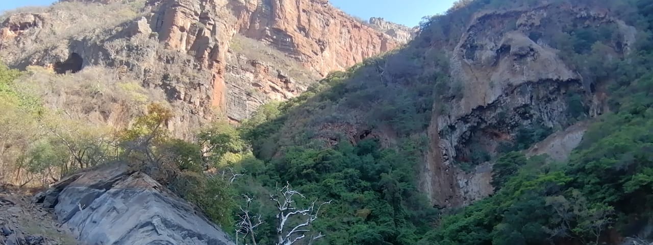 A mountain side with a skull staring back and a dam in the foreground