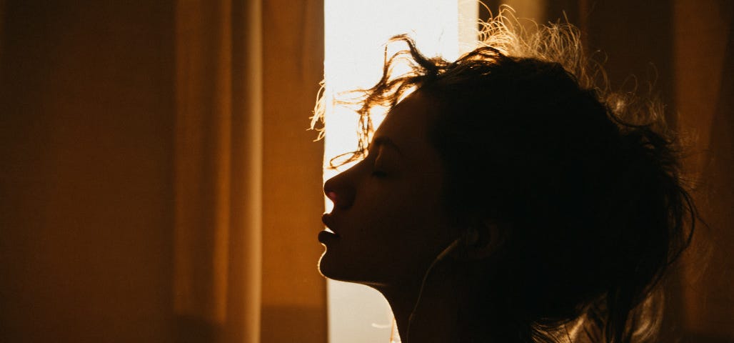 A relaxed woman’s silhouette against a sunset background.