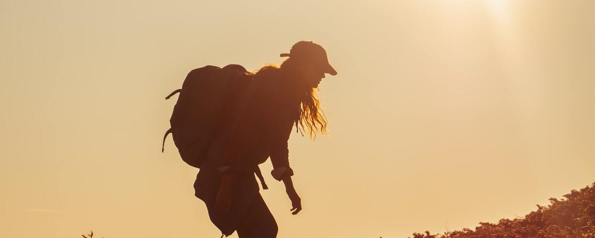 Hiker woman carrying a heavy backpack exhausted during the ascent. An active, healthy lifestyle is beneficial though beginnings can be tough.