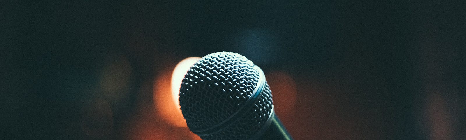 A close-up of a microphone with blurred lights in the background.