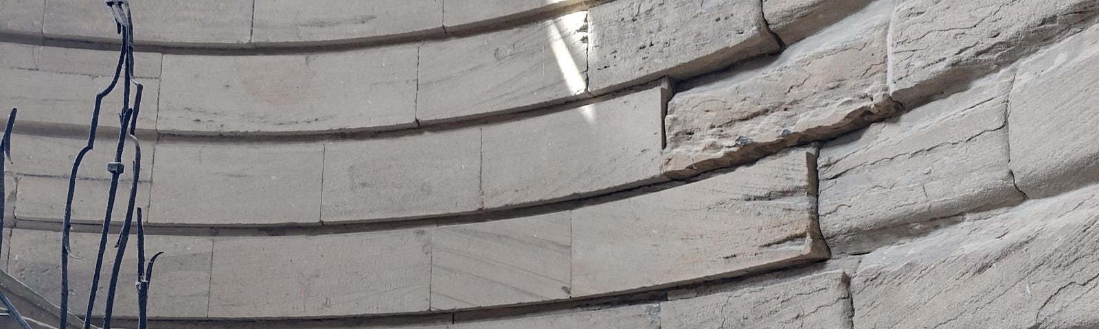 An old curved stone, spiral staircase with melted handrail.