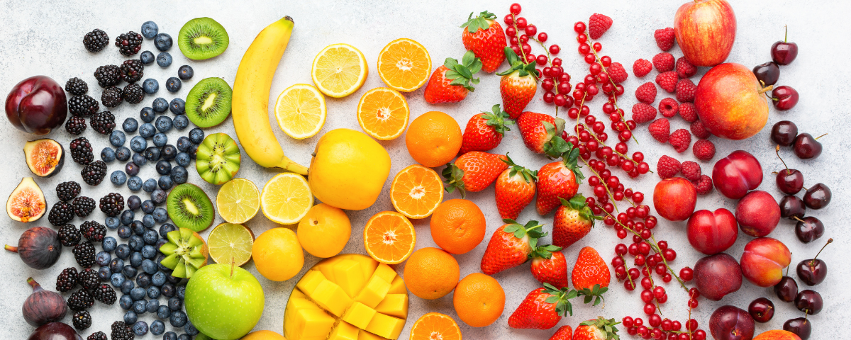 A variety of fruits arranged in colour order, through the colours of the rainbow.