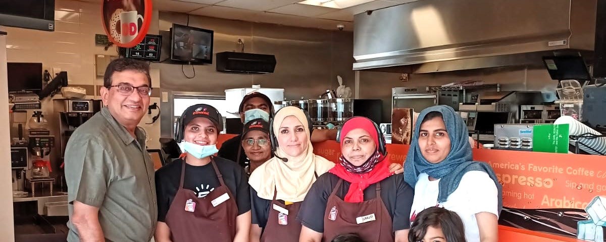 A group of women, two kids and a man standing inside a Dunkin Donut